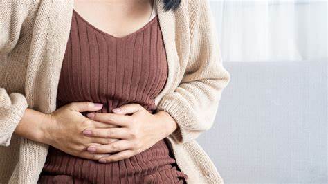 Woman clutching stomach in discomfort from menopause bloating.
