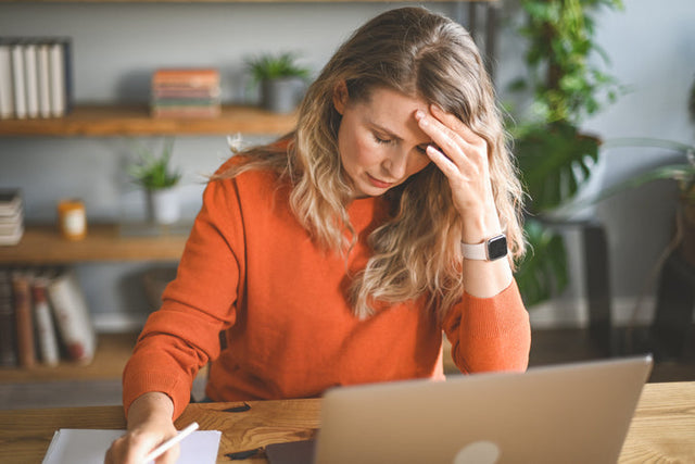 Woman struggling with memory loss during menopause at her desk.