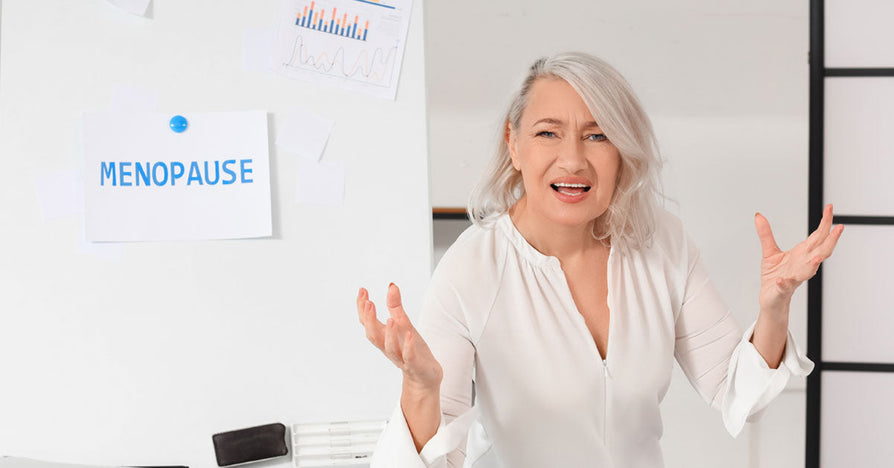 Frustrated woman struggling with menopause mood swings in office setting.